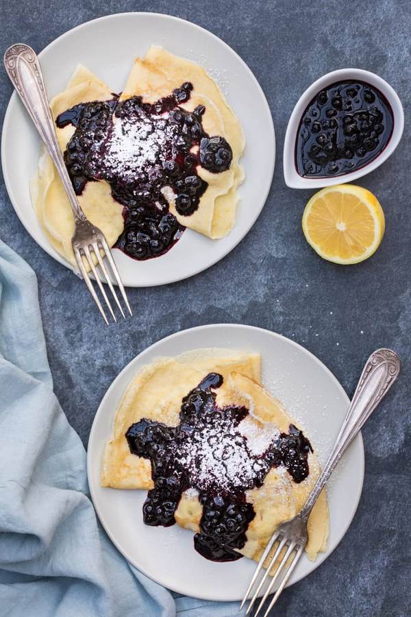 Thin golden crepes with lemon‑flavored batter and fresh blueberries, dusted with powdered sugar
