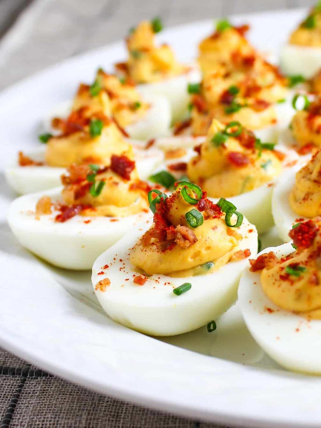 Bacon deviled eggs with creamy yolk filling, smoky bacon, paprika, and fresh chives