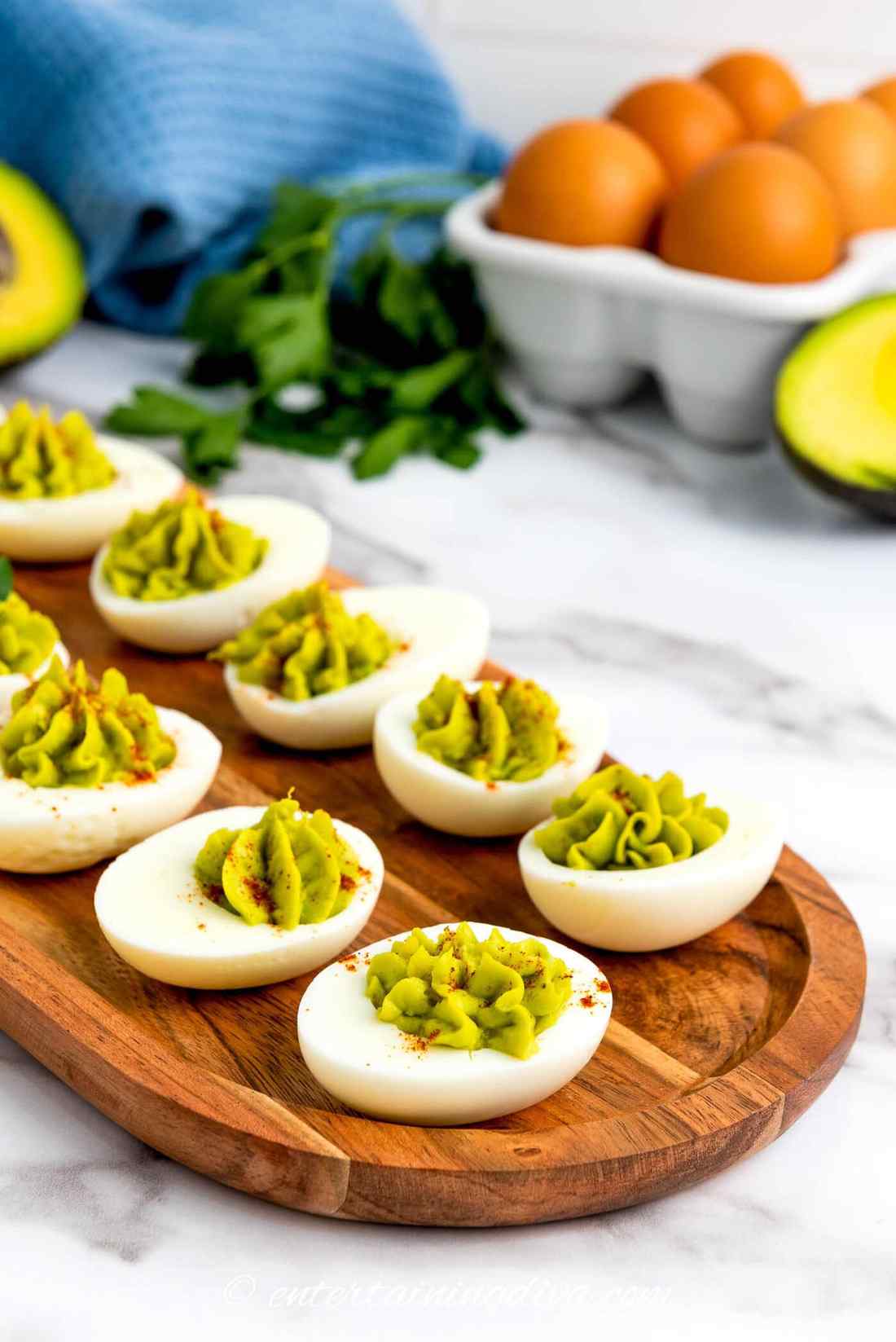 Avocado deviled eggs topped with crispy bacon bits, chives, and paprika