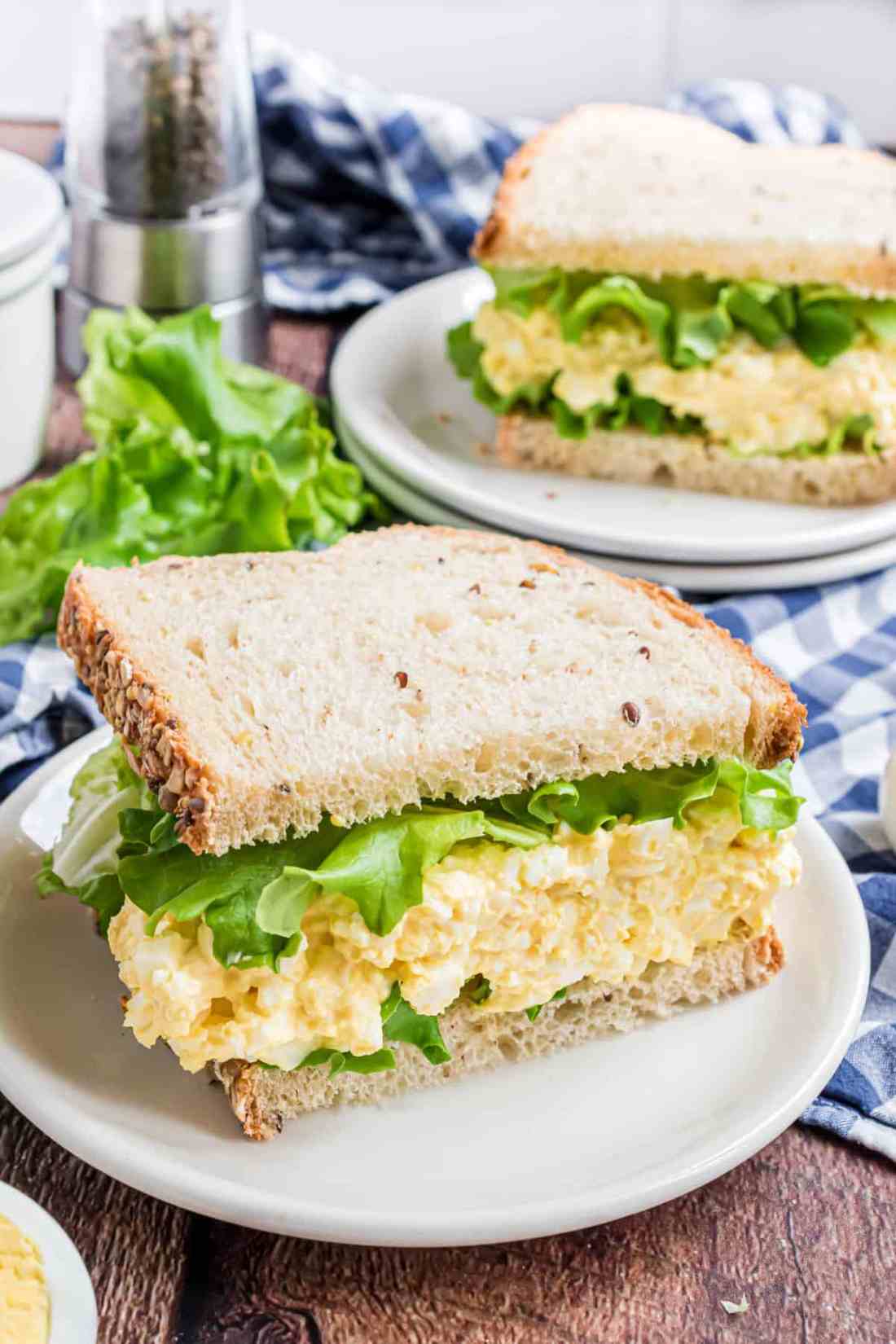 Egg salad sandwich with golden bread, creamy egg filling, crisp lettuce, and a drizzle of aioli