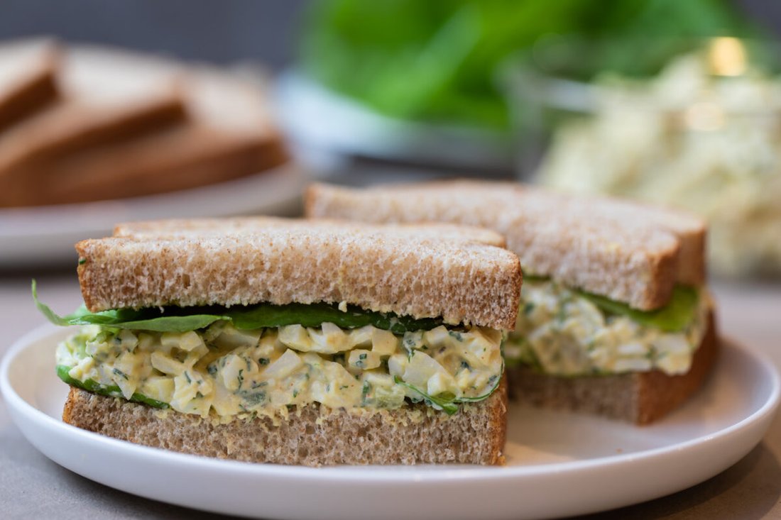 Creamy egg salad sandwich with chopped hard‑boiled eggs, fresh herbs, and crisp bread
