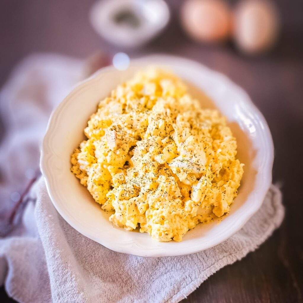 Classic creamy egg salad with chopped hard‑boiled eggs, tangy mayo, dill, and paprika on a fresh baguette