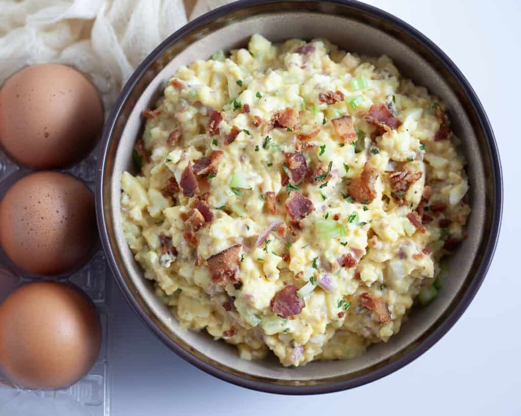 Bacon‑infused egg salad with chopped hard‑boiled eggs, creamy mayo, fresh herbs, crispy bacon bits, served on crisp lettuce leaves