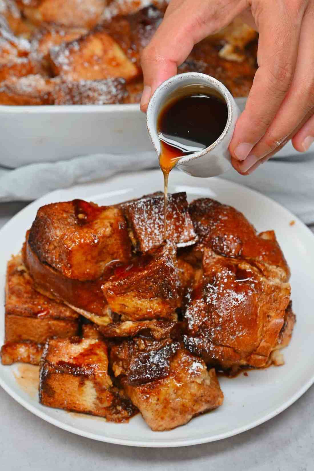 Warm, golden French toast casserole topped with glossy maple drizzle and toasted nuts