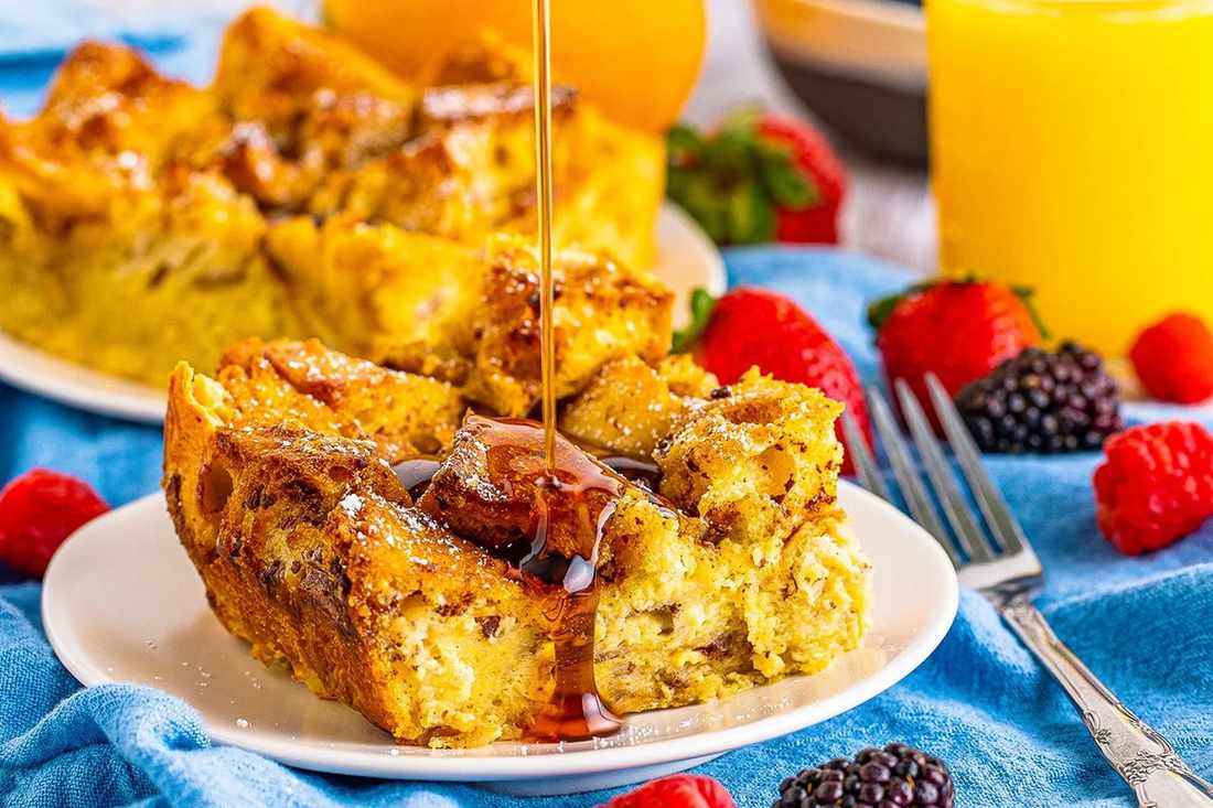 Golden baked French toast casserole, caramelized edges, drizzled with maple syrup and butter