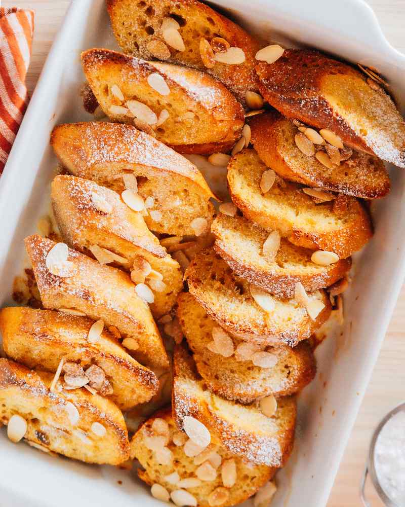Golden custardy bread cubes steaming with maple syrup, surrounded by warm fruit, a mouth-watering French toast casserole
