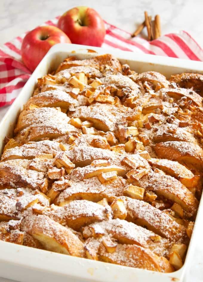 Warm cinnamon‑spiced apples atop golden custard‑soaked bread, glistening with butter