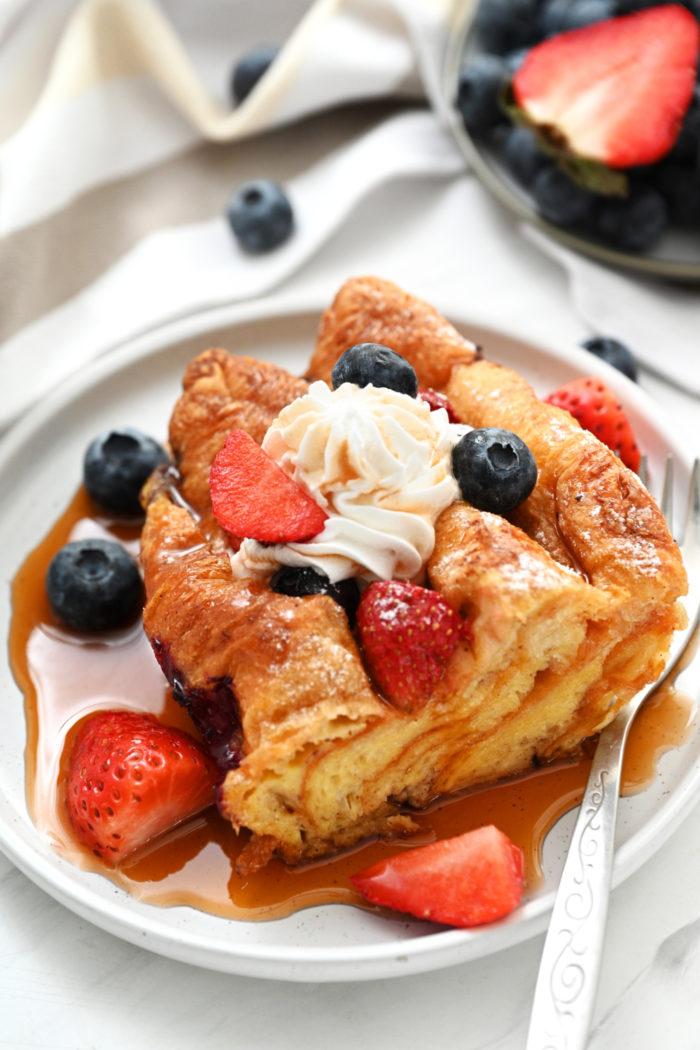 Classic French Toast Casserole with golden custardy bread cubes, warm fruit, and a drizzle of maple syrup