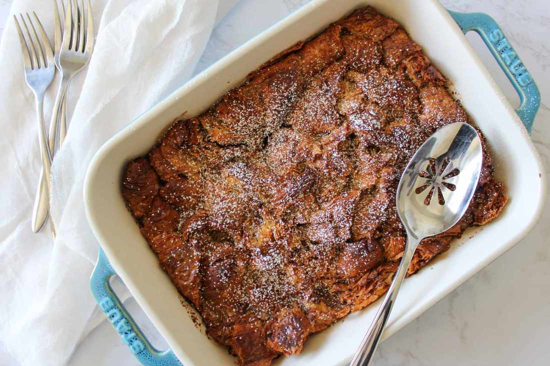 Decadent chocolate‑chip croissant French toast casserole, toasted pecans, caramelized crust, maple drizzle
