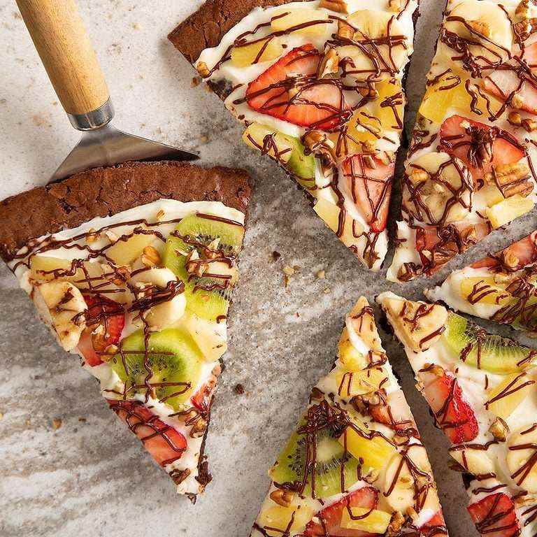 Chocolate brownie fruit pizza with cream cheese frosting topped with strawberries, blueberries, and blackberries