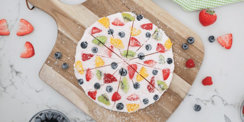 Chocolate brownie fruit pizza topped with cream cheese frosting, orange segments, blueberries, and kiwi