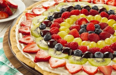 Sugar cookie fruit pizza topped with cream cheese frosting, apricot glaze, strawberries, kiwi, blueberries