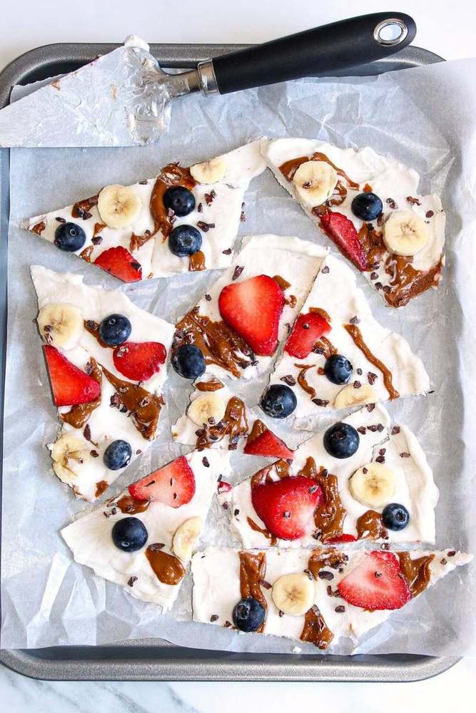 Sugar cookie fruit pizza topped with cream cheese frosting, pineapple chunks, toasted coconut, and kiwi