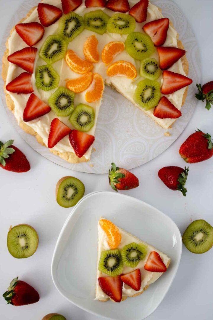 Sugar cookie fruit pizza topped with cream cheese frosting, watermelon cubes, fresh mint, and kiwi