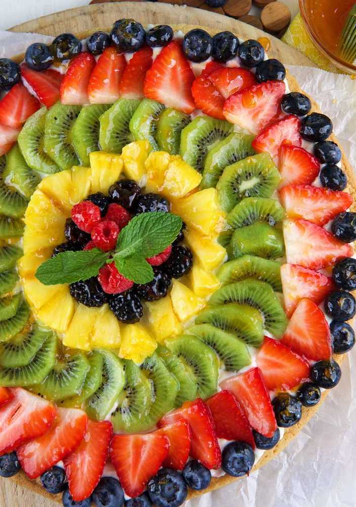 Sugar cookie crust with basil‑infused cream cheese frosting, sliced strawberries, and balsamic glaze, gourmet fruit pizza