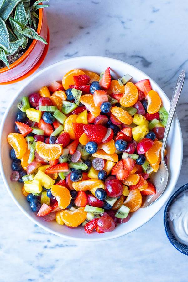 Color‑burst rainbow fruit salad with strawberries, orange, kiwi, grapes, and citrus‑mint dressing