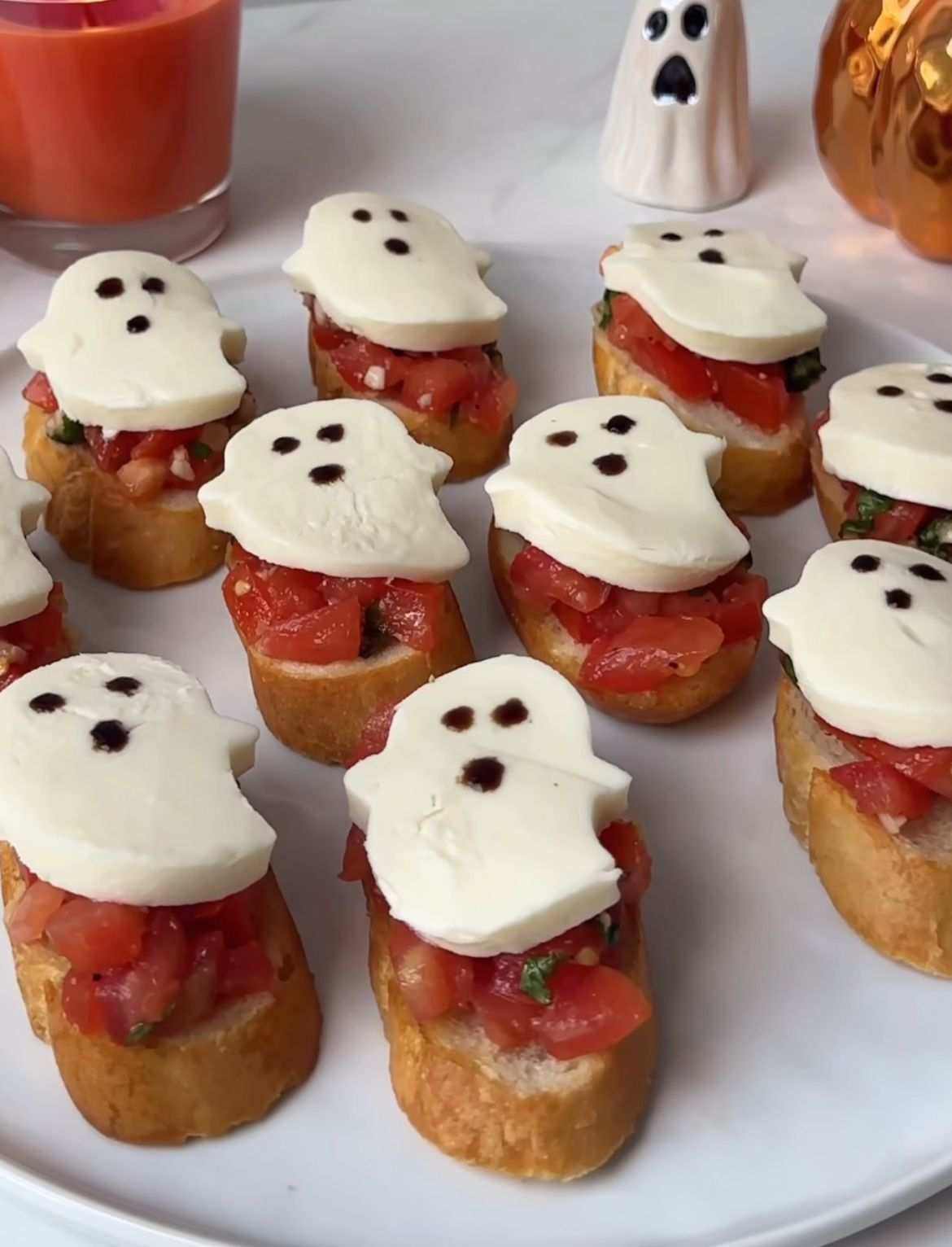 Baguette slices topped with ghost-shaped mozzarella, tomato, and basil.