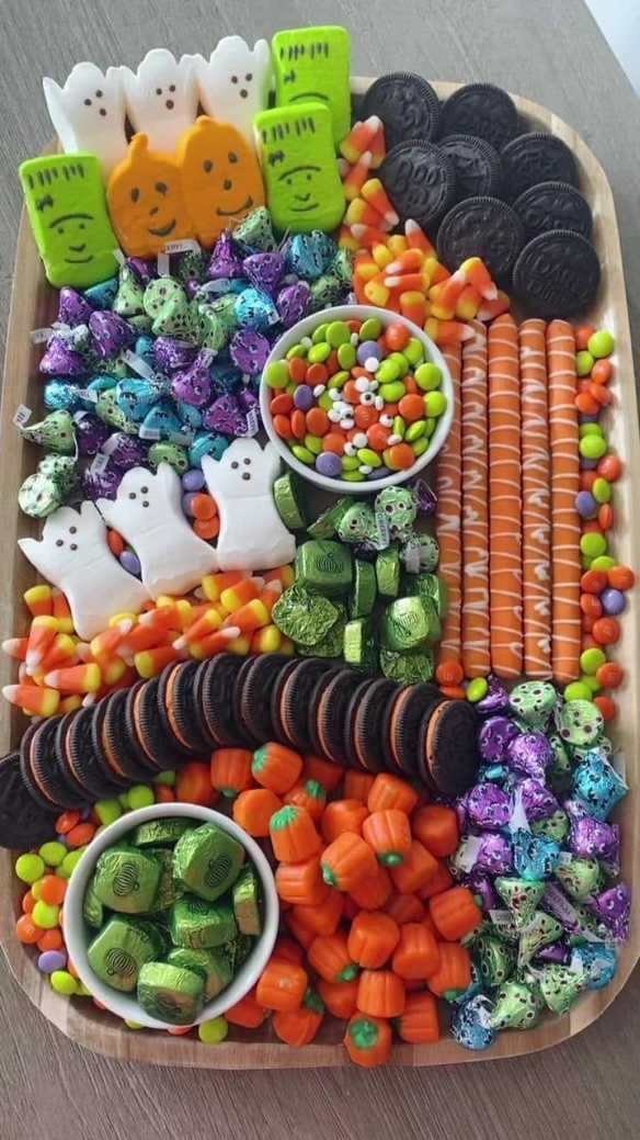 Colorful charcuterie board piled with candy corn, marshmallow Peeps, Oreo “tombstones,” and gummy worms.