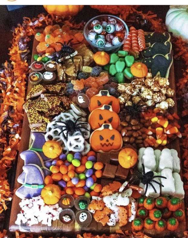 A board with chocolate, gummy candies, and cookies arranged in Halloween shapes.