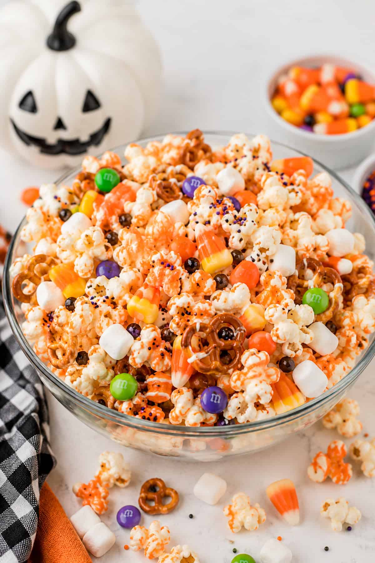 Bowl of kettle corn popcorn mixed with pretzel rods, orange candy corn, and caramel candies.