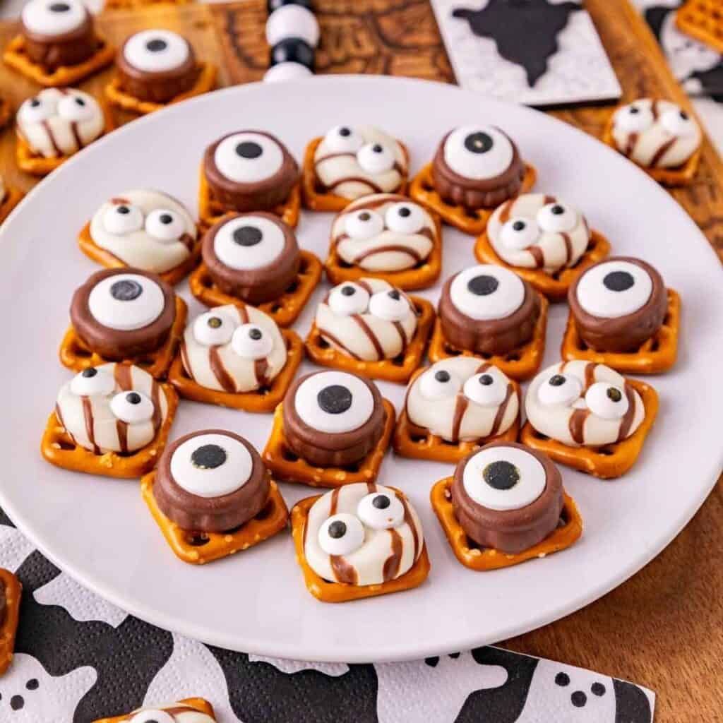 Mini pretzel sticks wrapped around caramel-filled chocolate squares, dusted with orange sprinkles.