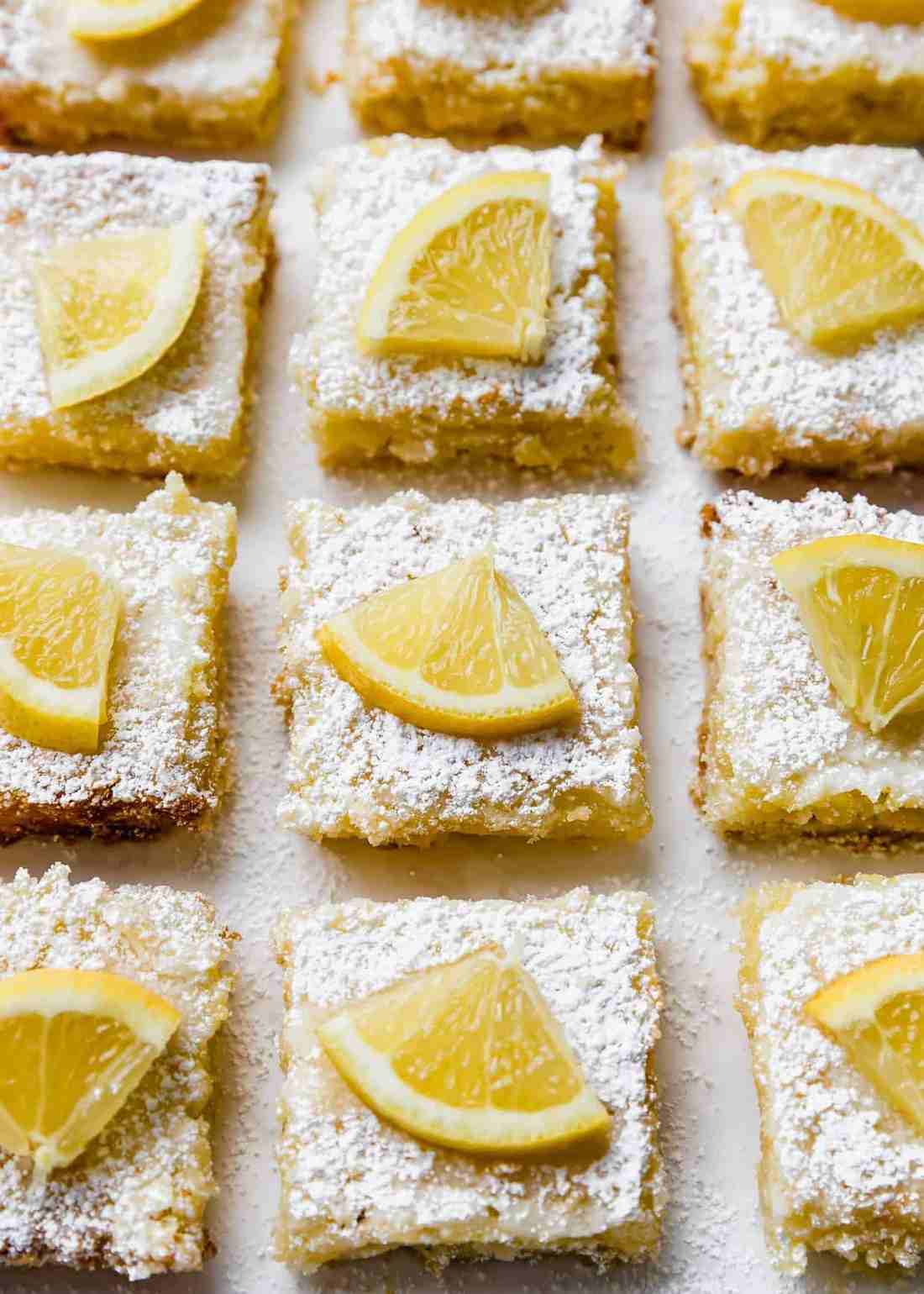 Golden lemon bars with buttery shortbread crust, tangy lemon curd, dusted with powdered sugar