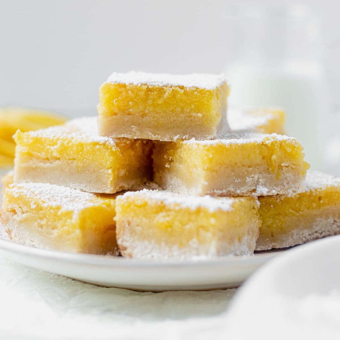 Soft lemon bars on a golden oat‑rice crust, sprinkled with icing sugar