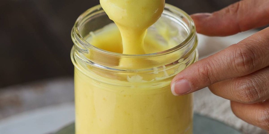 Creamy vegan lemon curd in a glass bowl, bright citrus, smooth, with a sprig of mint