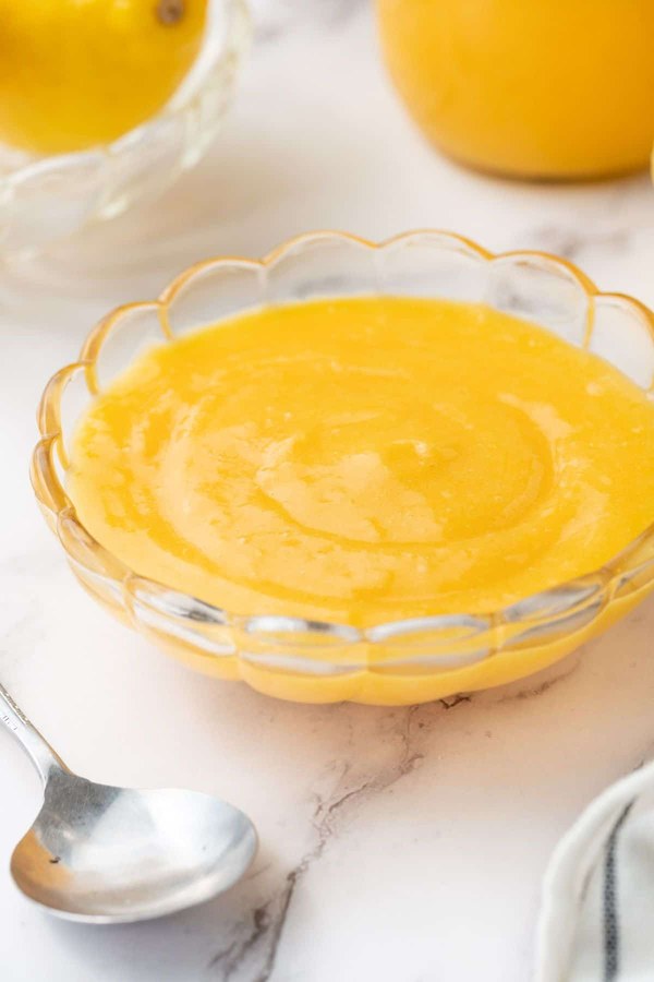 Classic stovetop lemon curd simmering, bright yellow, creamy, with lemon zest garnish