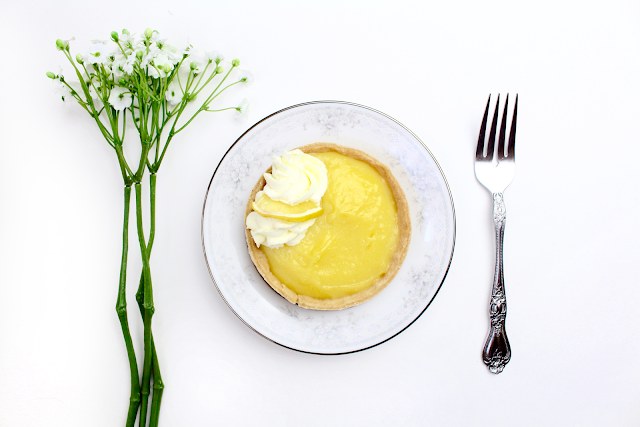 Lemon curd tart on almond crust, bright citrus, smooth filling, garnished with toasted almond slivers