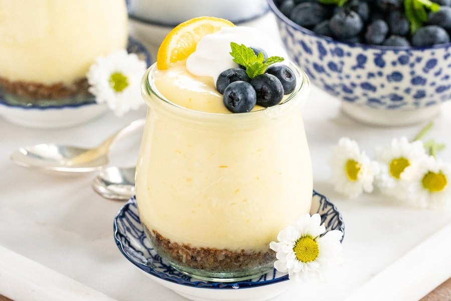 Mini mousse cups filled with lemon curd, topped with whipped cream and zest