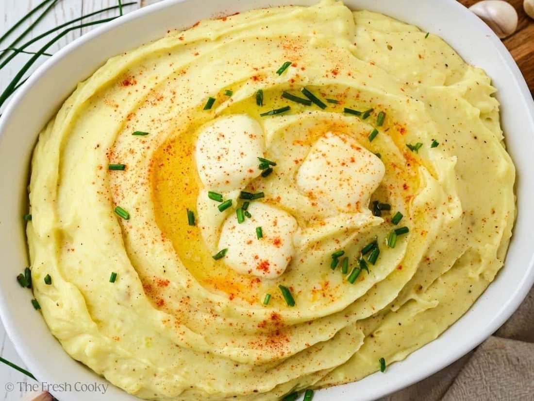 Fluffy mashed potatoes topped with roasted garlic cloves, melted herb butter, and fragrant thyme