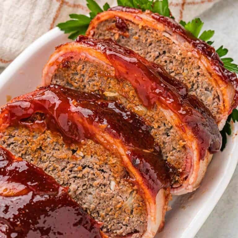 Cheesy bacon-wrapped meatloaf with herb-infused glaze, golden crust, and creamy interior