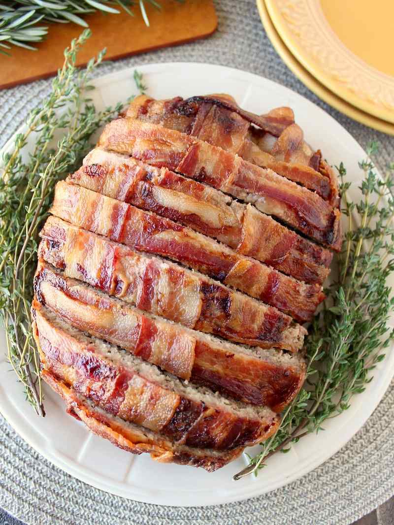 Cheesy bacon-wrapped meatloaf with melted mozzarella, juicy beef interior, crispy bacon edges