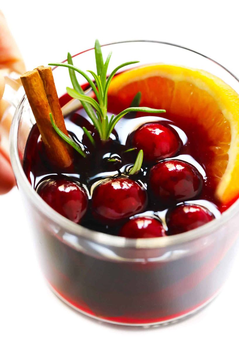 Vibrant cranberry mulled wine with floating fresh cranberries, sliced orange, and star anise in mug