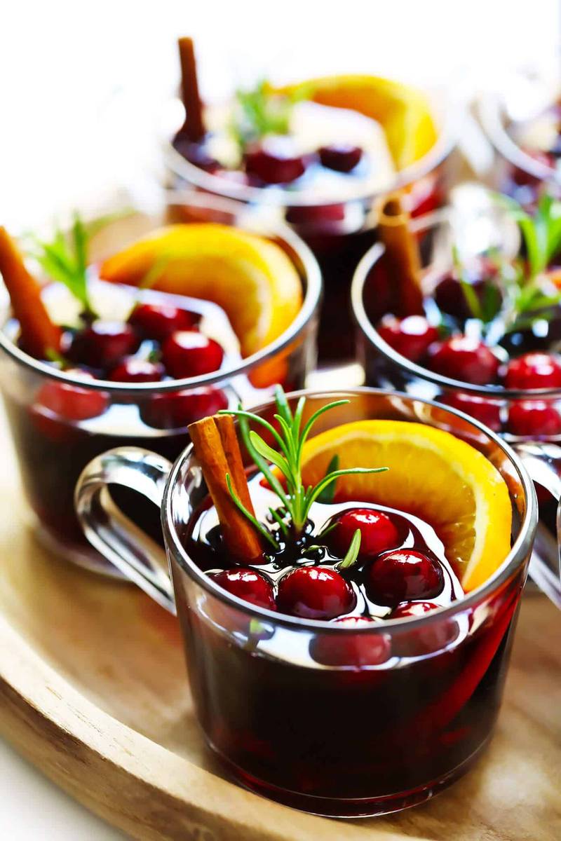 Cranberry mulled wine with fresh rosemary sprigs, orange slices, and cranberries in clear glass