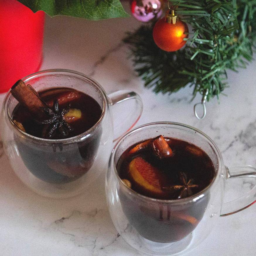Spicy homemade mulled wine with fresh ginger slices, cracked black peppercorns, and orange peel