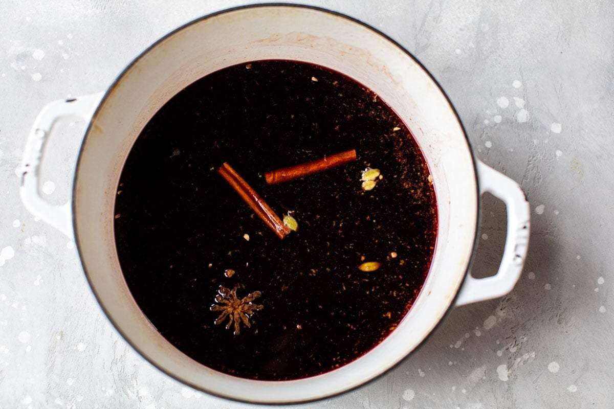 Slow cooker spiced red wine loaded with sliced clementines, cloves, and cinnamon sticks