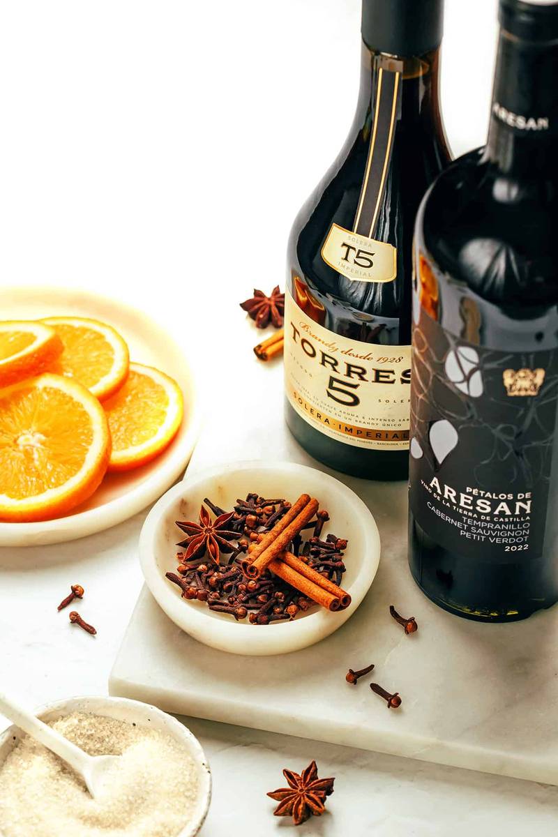 Classic German glühwein with ruby-red wine, floating orange slices, and whole cinnamon sticks in traditional mugs.