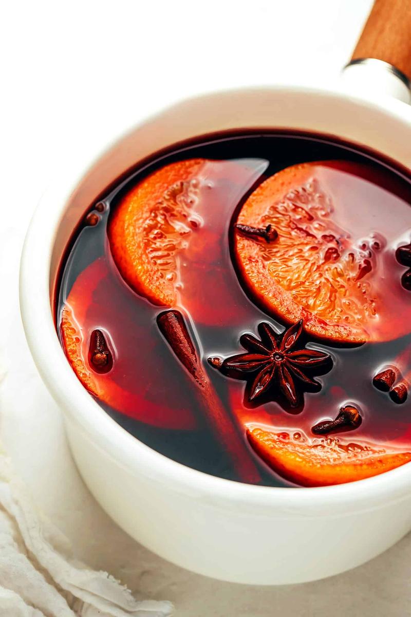 Clementine bourbon mulled wine featuring ruby-red wine, citrus wheels, and whole cinnamon sticks in mugs.