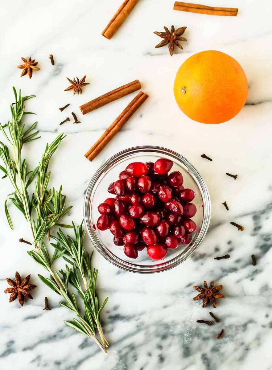 Cardamom citrus mulled white wine with floating orange slices, cinnamon, and whole spices in mugs.