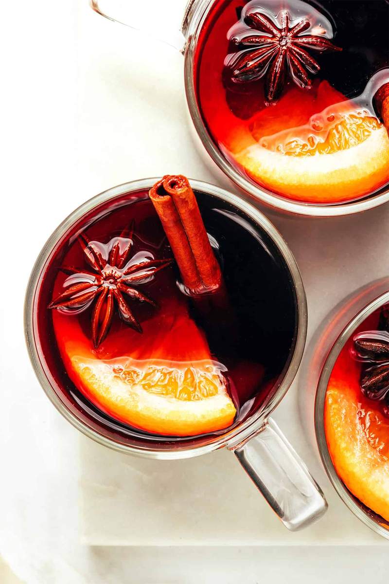 Blackberry nutmeg mulled wine featuring deep ruby-red wine, dark berries, and cinnamon sticks in mugs.