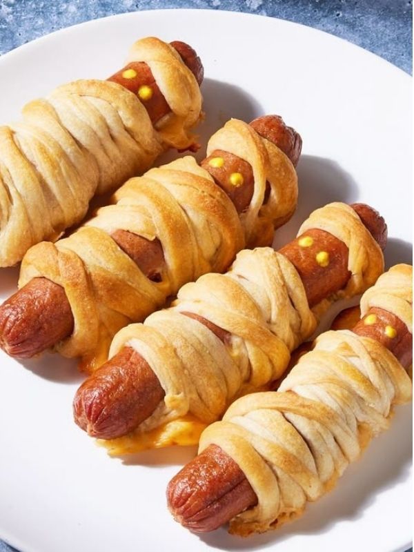 Mini hot dogs wrapped in crescent roll “bandages,” topped with mustard eyes and ketchup “blood.”