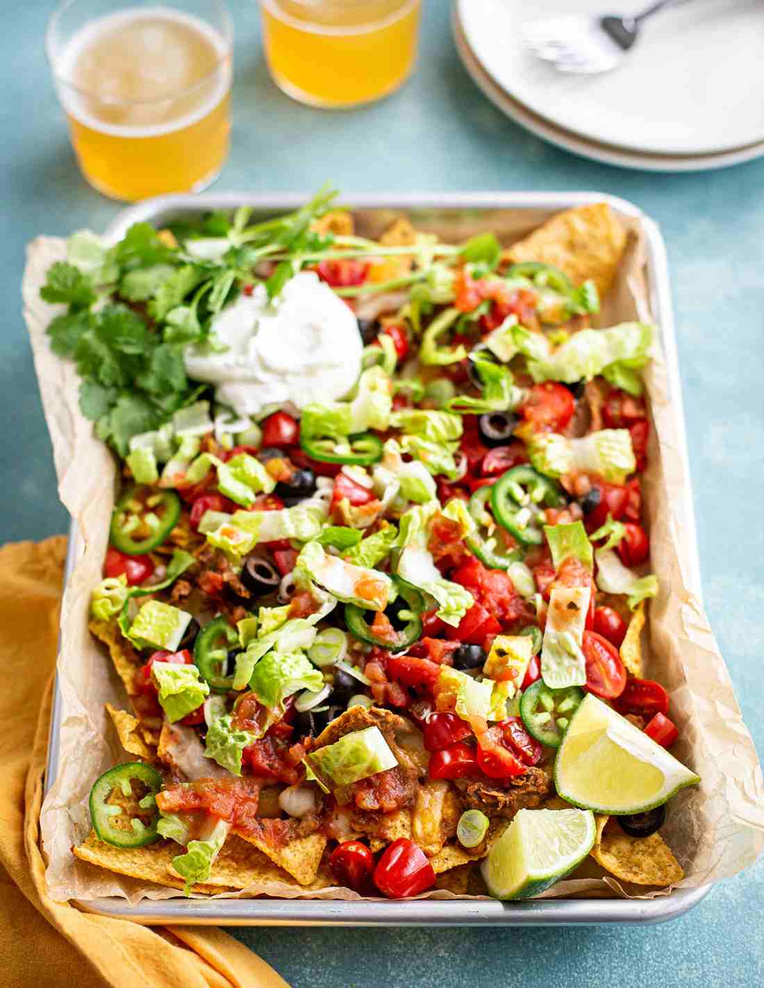 Ultimate cheesy fiesta nachos topped with melted pepper jack cheese, diced tomatoes, guacamole, and loaded tortilla chips