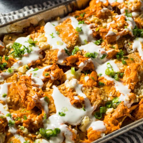 Sheet pan buffalo chicken nachos loaded with melted mozzarella, jalapeños, guacamole, and crunchy tortilla chips