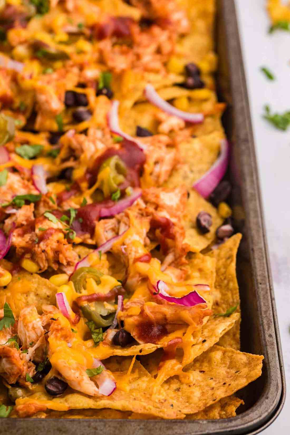 Smoky BBQ chicken nachos drizzled with barbecue sauce, melted smoked gouda cheese, jalapeños, and tortilla chips