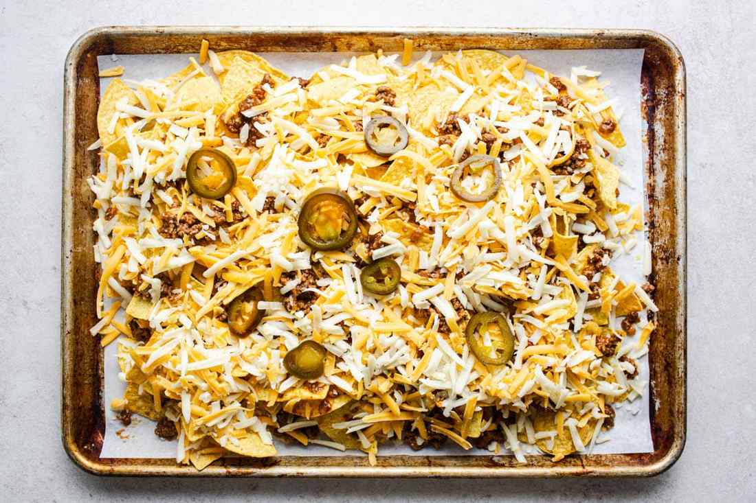 Classic loaded beef nachos with melted cheddar cheese, jalapeños, guacamole, sour cream, and crispy tortilla chips.