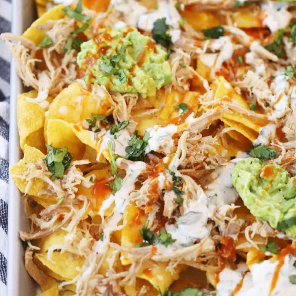 Carnitas pork nachos smothered in melted queso fundido cheese, jalapeños, guacamole, sour cream, and tortilla chips.