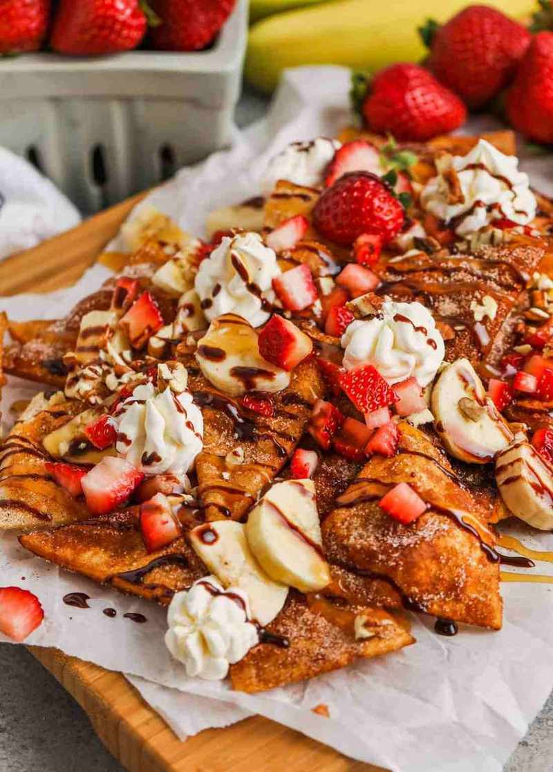 Sweet dessert nachos styled with melted cheese substitute, candied jalapeños, guacamole, sour cream, loaded tortilla chips