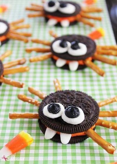 Oreo halves with melted chocolate bodies, pretzel legs, and colorful candy eyes perched on a spooky platter.